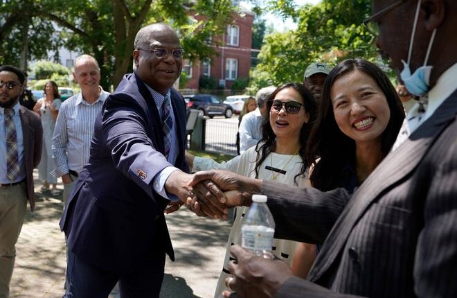 Michael Cox, left, who has been named as the next Boston police commissioner, shakes hands while greeting people as Boston Mayor Michelle Wu, right, looks on Wednesday, July 13, 2022. Cox, who was beaten more than 25 years ago by colleagues who mistook him for a suspect served in multiple roles with the Boston Police Department before becoming the police chief in Ann Arbor, Michigan, in 2019.