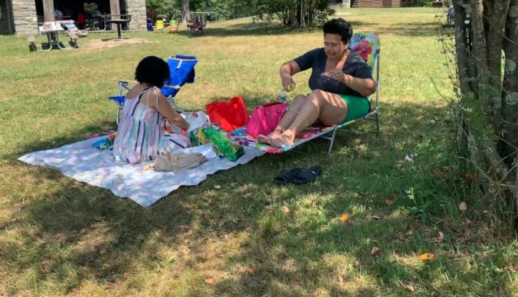 Rosa Chavez, of New York City, applies sunscreen as she and friend Arlene Rodriguez visit Promised Land State Park, Sunday, July 24, 2022 in Pennsylvania's Pocono Mountains in Greentown, Pa. Residents around the Northeast braced for potentially recor